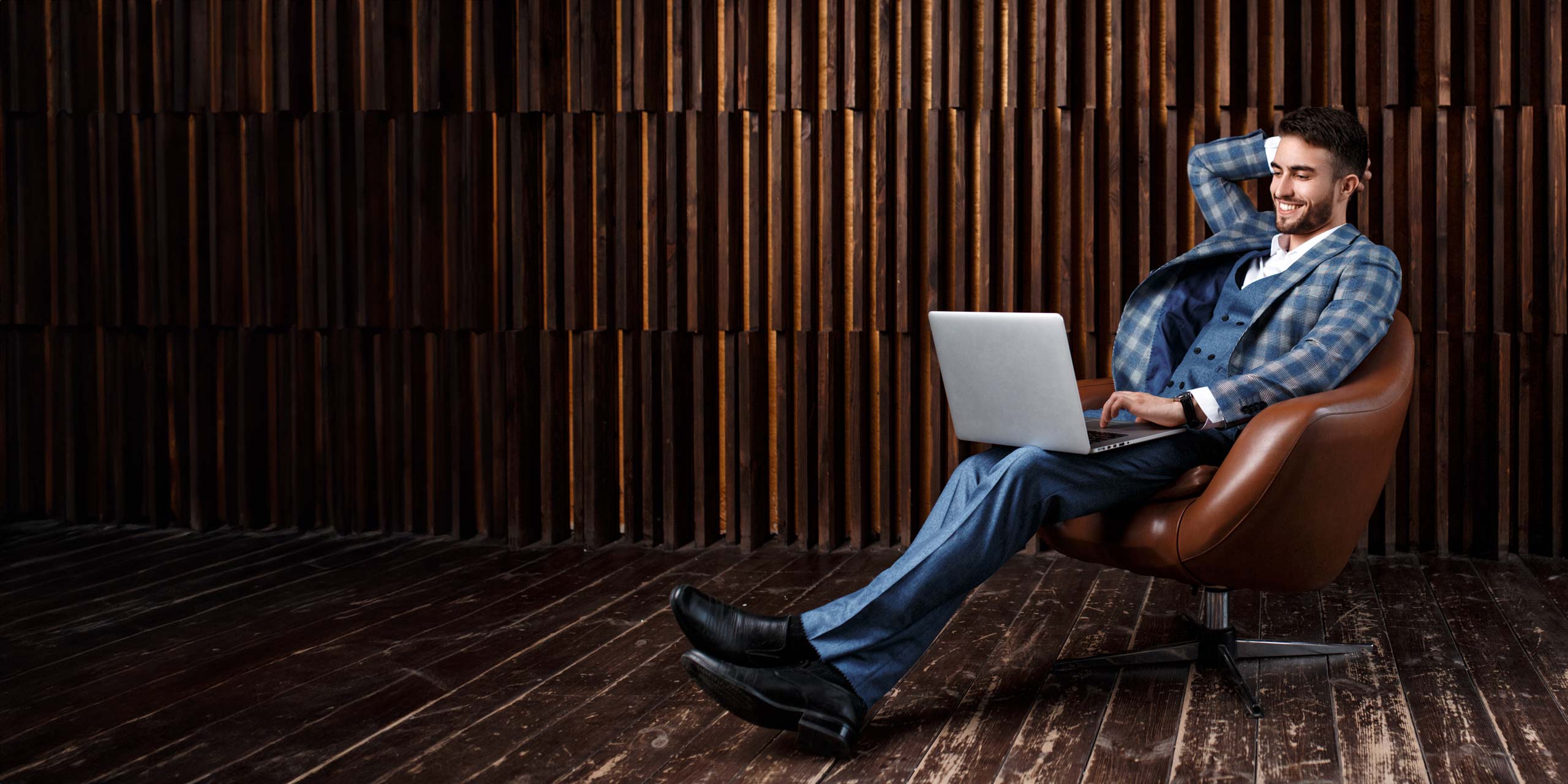 Junger Businessmann sitzt auf Sofa vor einem Laptop